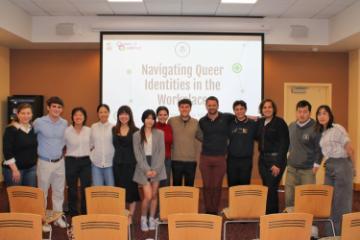 Members of Queer and Qualified posing for a photo in a classroom in front of a projector screen