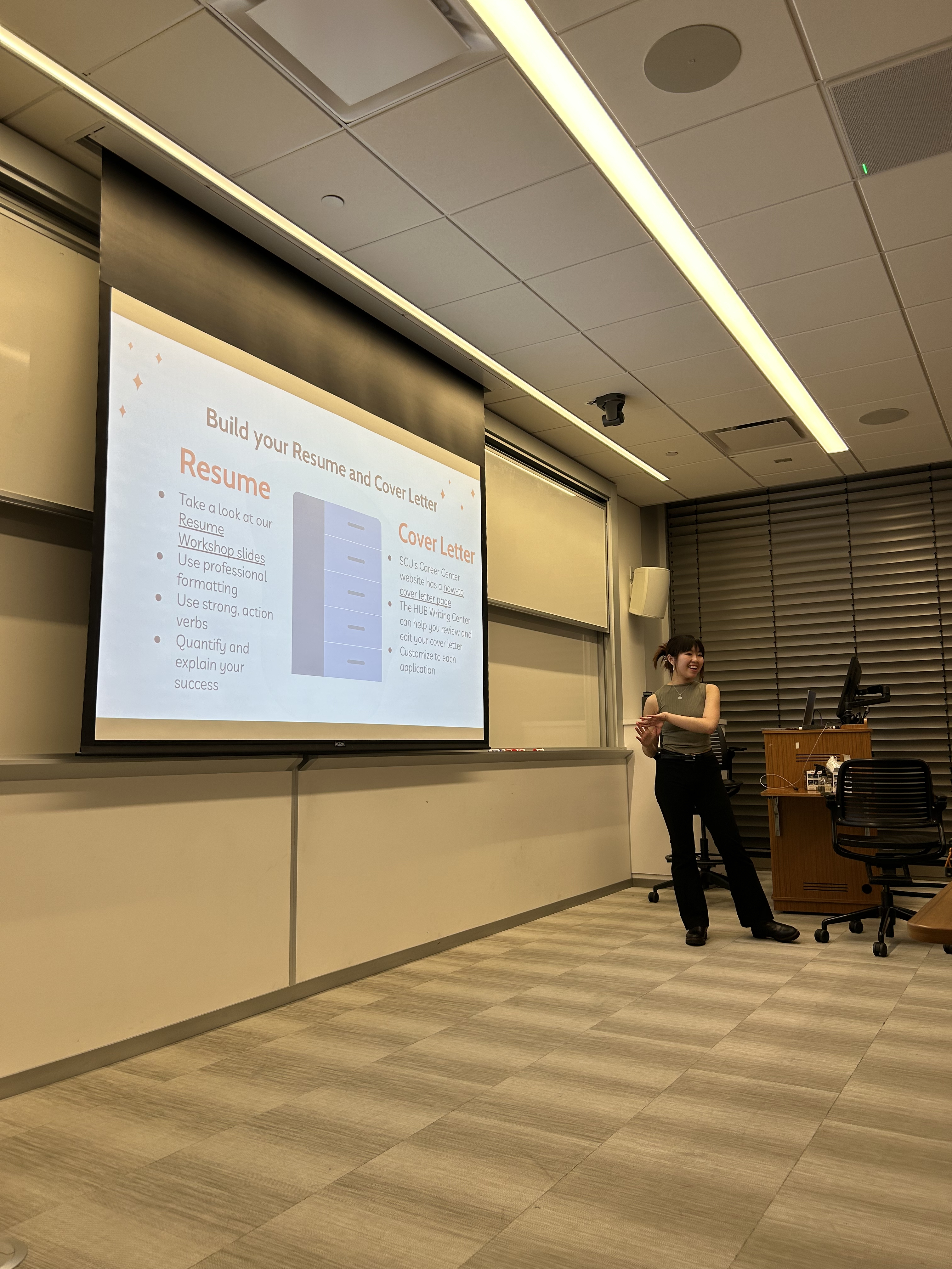 Member of Queer and Qualified presenting in front of a project screen during a resume workshop