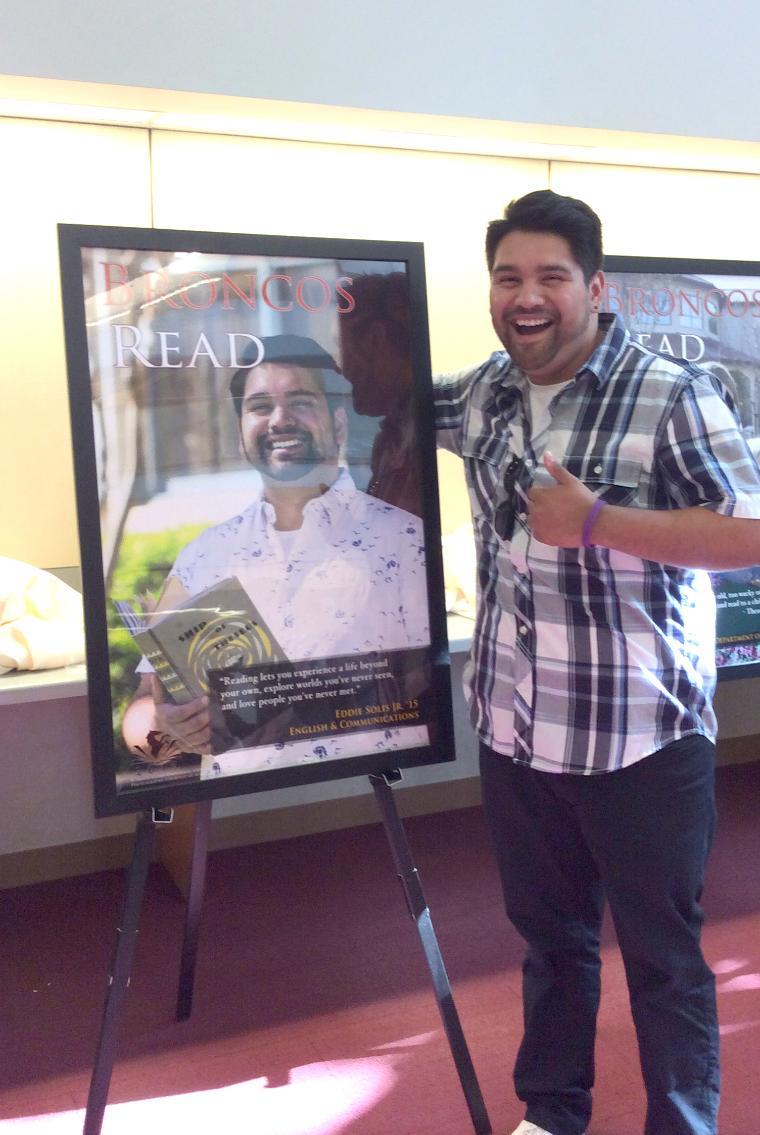 Eddie Solis Jr. (English Major) joyfully poses next to his 2015 Broncos Read poster.