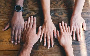 hands on a table representing people of different races