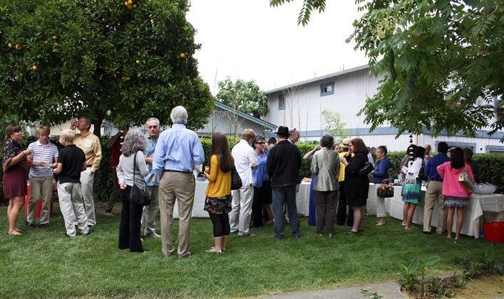 A large group of people gathered outdoors for a graduation brunch.