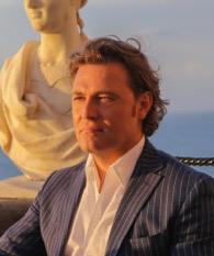 Man in a suit with the Amalfi Coast backdrop at sunset.