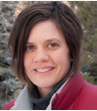 A person wearing a red jacket outdoors with a snowy background.