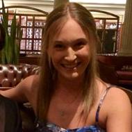 A woman smiling in a restaurant setting.