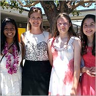 Four women standing together outdoors and smiling.