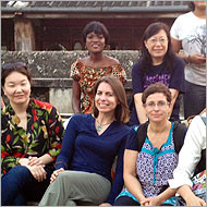 A group of six people sitting and smiling outdoors.