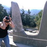 A person taking a photo near a monument in Athens.