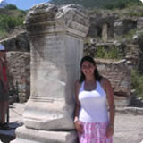 A person standing beside a stone column in an ancient ruin site.