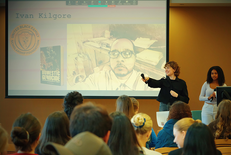 Gianna Madden holds out a microphone to capture applause for guest speaker Ivan Kilgore, an incarcerated author and founder of the United Black Family Scholarship Foundation. Taken by Gwyneth Choi ’26.