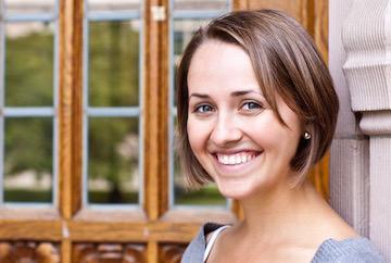 A woman smiling in front of a window.