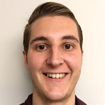 A person smiling, wearing a dark shirt against a plain background. image link to story