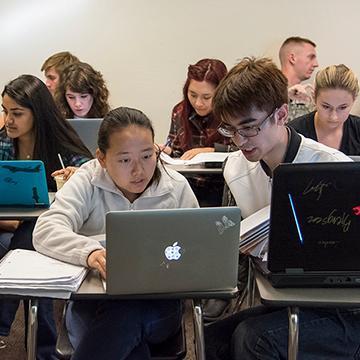 Students in a Computer Science class using laptops in a classroom setting. image link to story