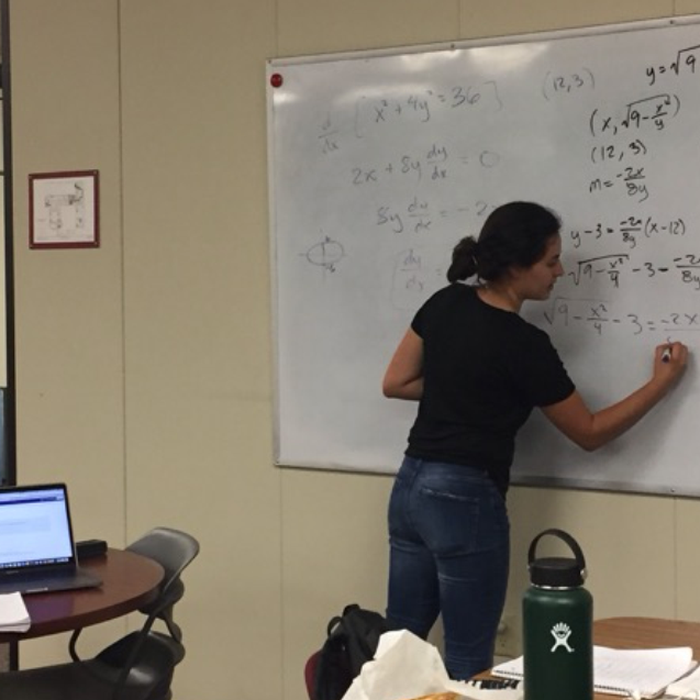 Two people working at a whiteboard and on a laptop. image link to story