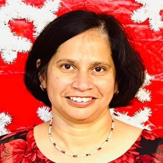 A person smiling in front of a red and white snowflake background.