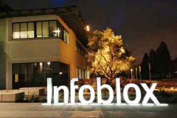 Illuminated Infoblox sign, trees, and building at night outside corporate headquarters. image link to story