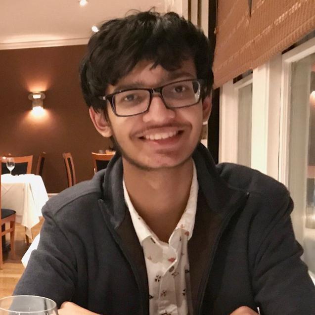 A person sitting at a table in a restaurant, smiling. image link to story