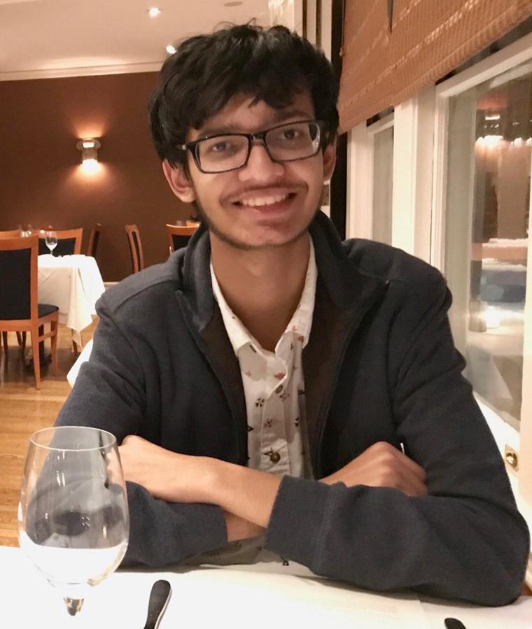 A person sitting at a table in a restaurant, smiling. image link to story