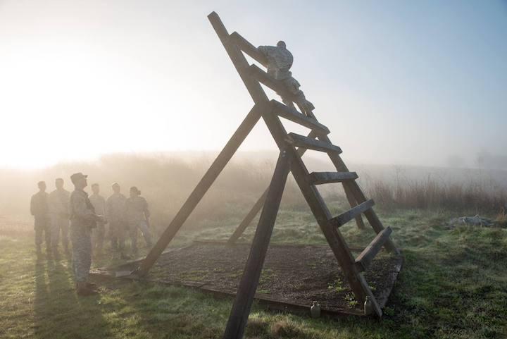 Wooden watchtower ladder overlooking a foggy field at sunrise.