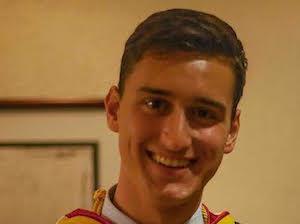 A person named Jesse in graduation attire smiling.