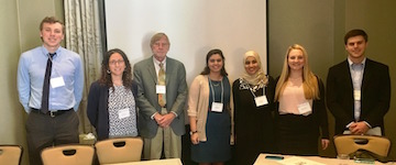Seven people standing together in conference setting.