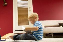 A child in a striped shirt sitting on a bed.