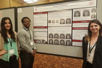 Three people presenting a research poster titled 'Koopmann-Holm Lab'.