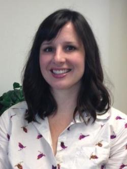 A person smiling, wearing a white shirt with small designs.