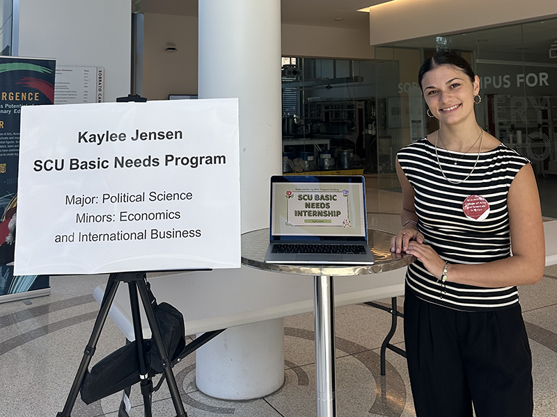 Kaylee Jensen standing next to her SCU Basic Needs presentation