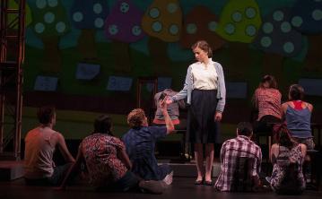 Performers on stage with a colorful backdrop. 