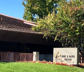 Outside of Louis B. Mayer Theatre showing the brass name sign with theatre masks on a concrete mount