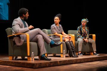 3 panelists seated on a stage: a black man, a white woman, a black woman