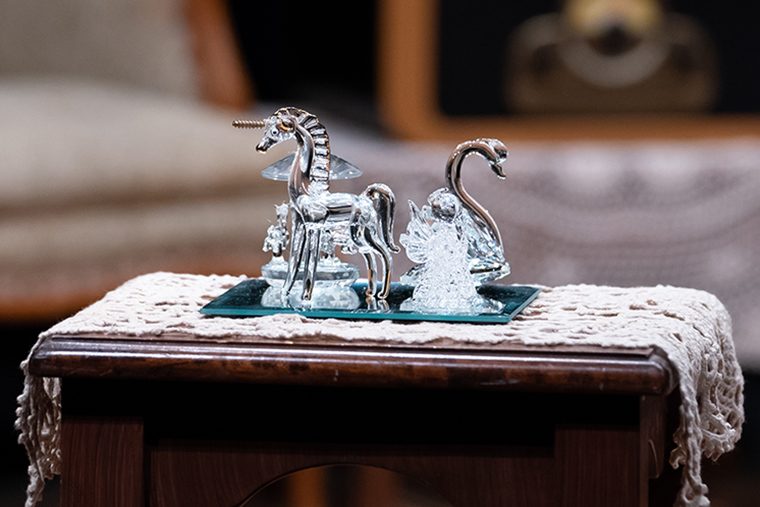 Two glass animals on a tray atop a wooden table.