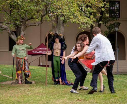 Two cast members carrying another cast member away dramatically