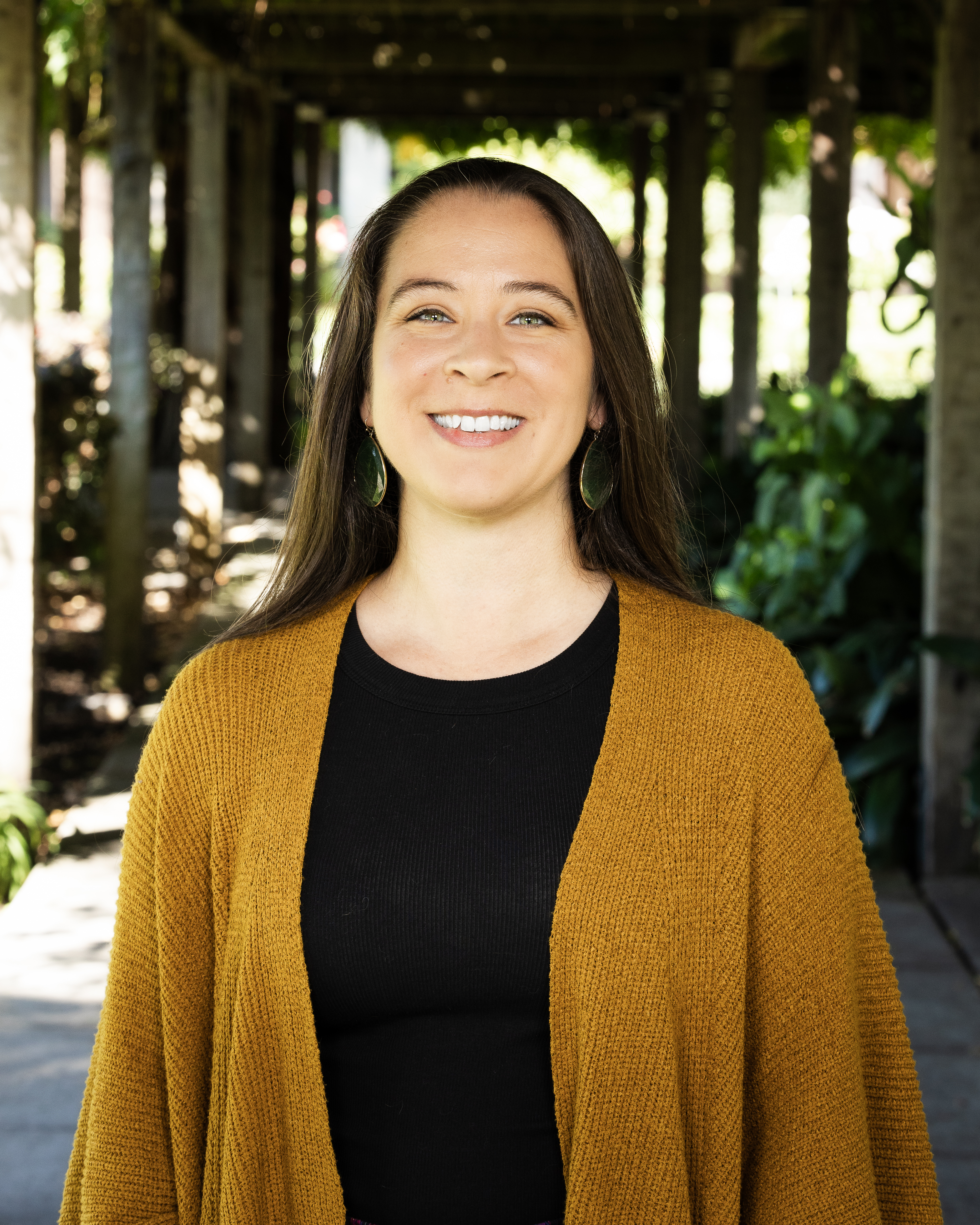 Woman smiling at camera wearing black shirt and golden wrap