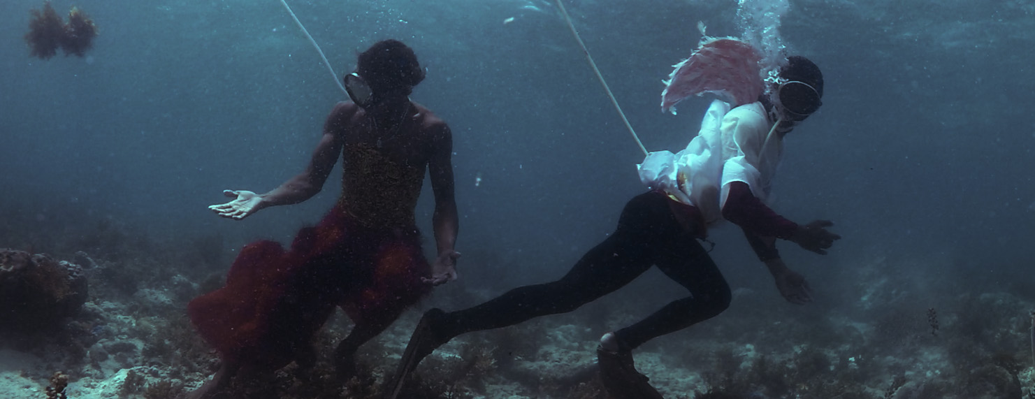 Video still of two figures underwater