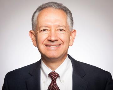 A man in a suit smiling at the camera.