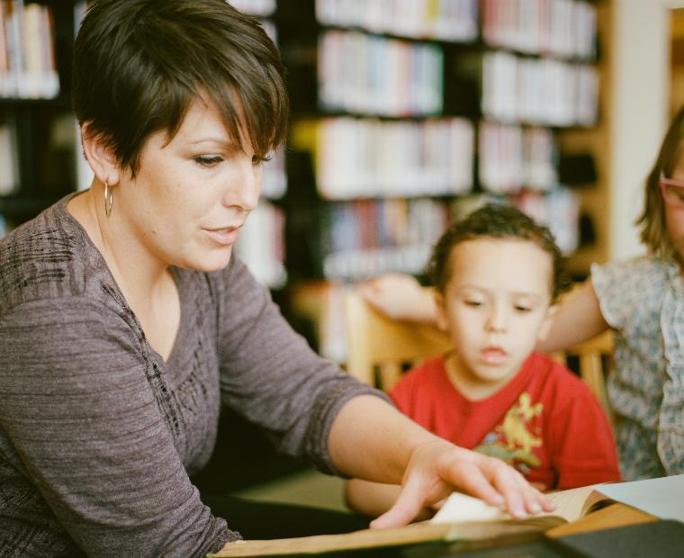 Teacher helping a young student in a classroom setting.