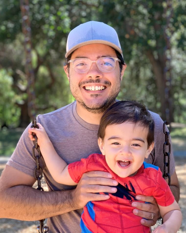 A man holding a smiling child outdoors.