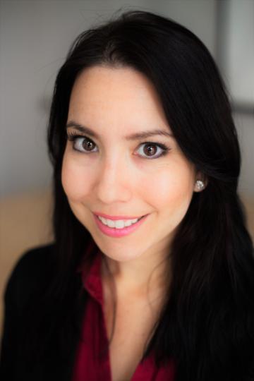 Smiling woman in professional attire with neutral background.