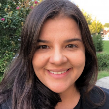 Dr. Sophia Rodriguez smiling outdoors with greenery in the background.