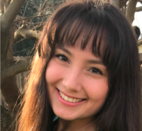 A person smiling with trees in the background.