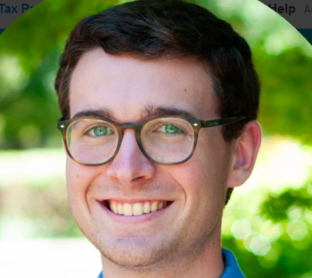 A person with glasses smiling outdoors.