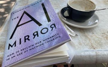 book and coffee cup on a saucer on a table