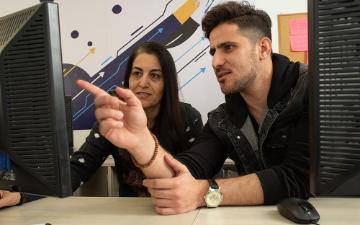 Two people discussing dataset labeling at computer screens. 