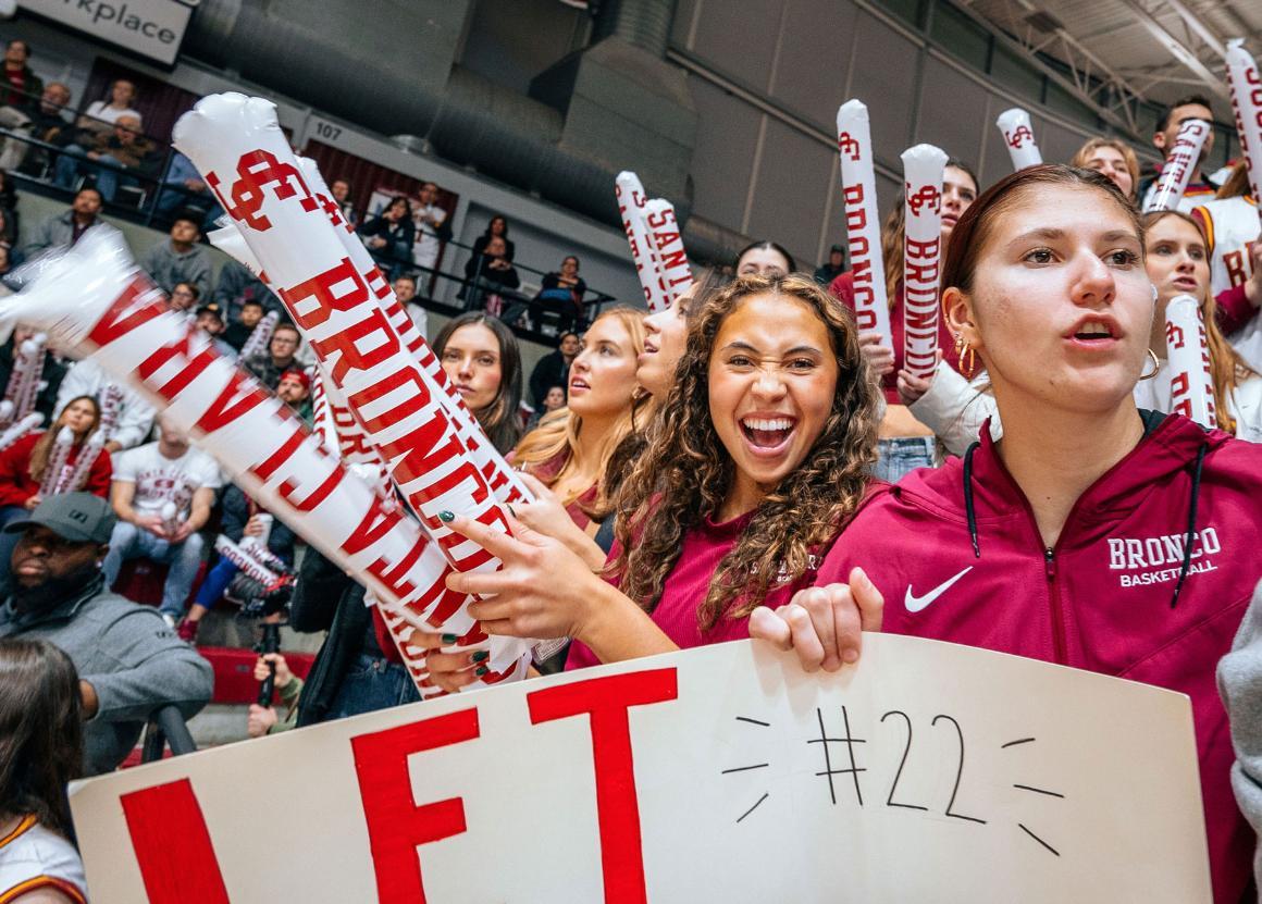 SCU students cheer while holding signs at a sports event