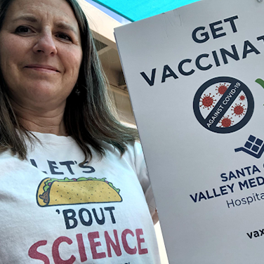 Professor holding up a sign that says get vaccinated