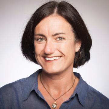 A person smiling in a portrait with a light background.