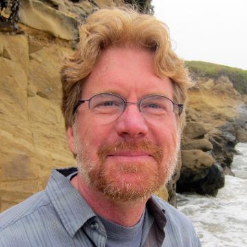 A person standing by rocky cliffs and the ocean.