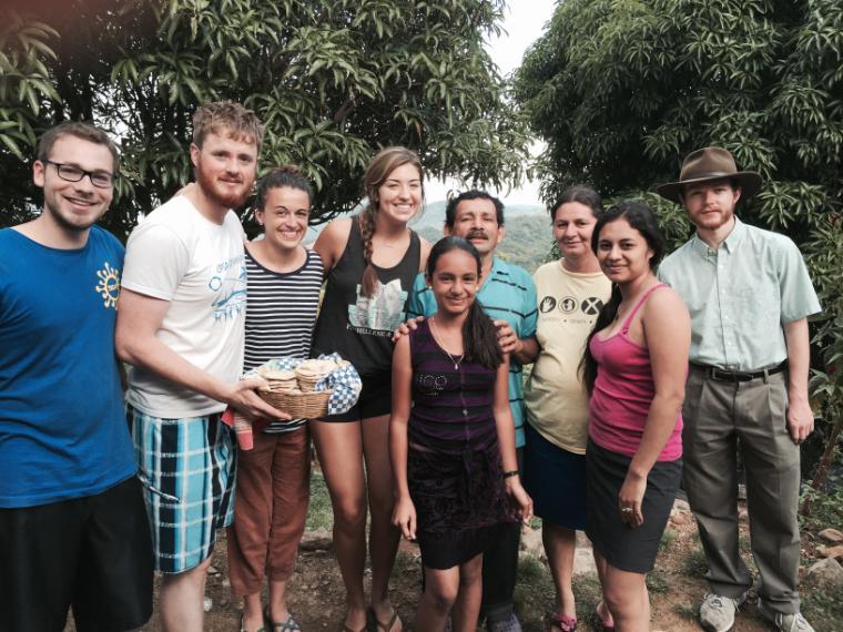 Group of people posing outdoors under trees during an immersion trip.