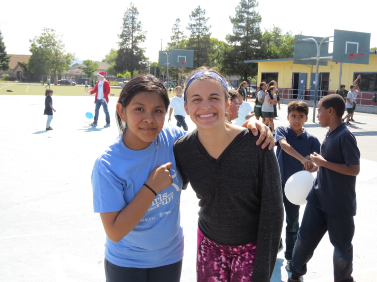 Two people posing outside with their arms around each other.